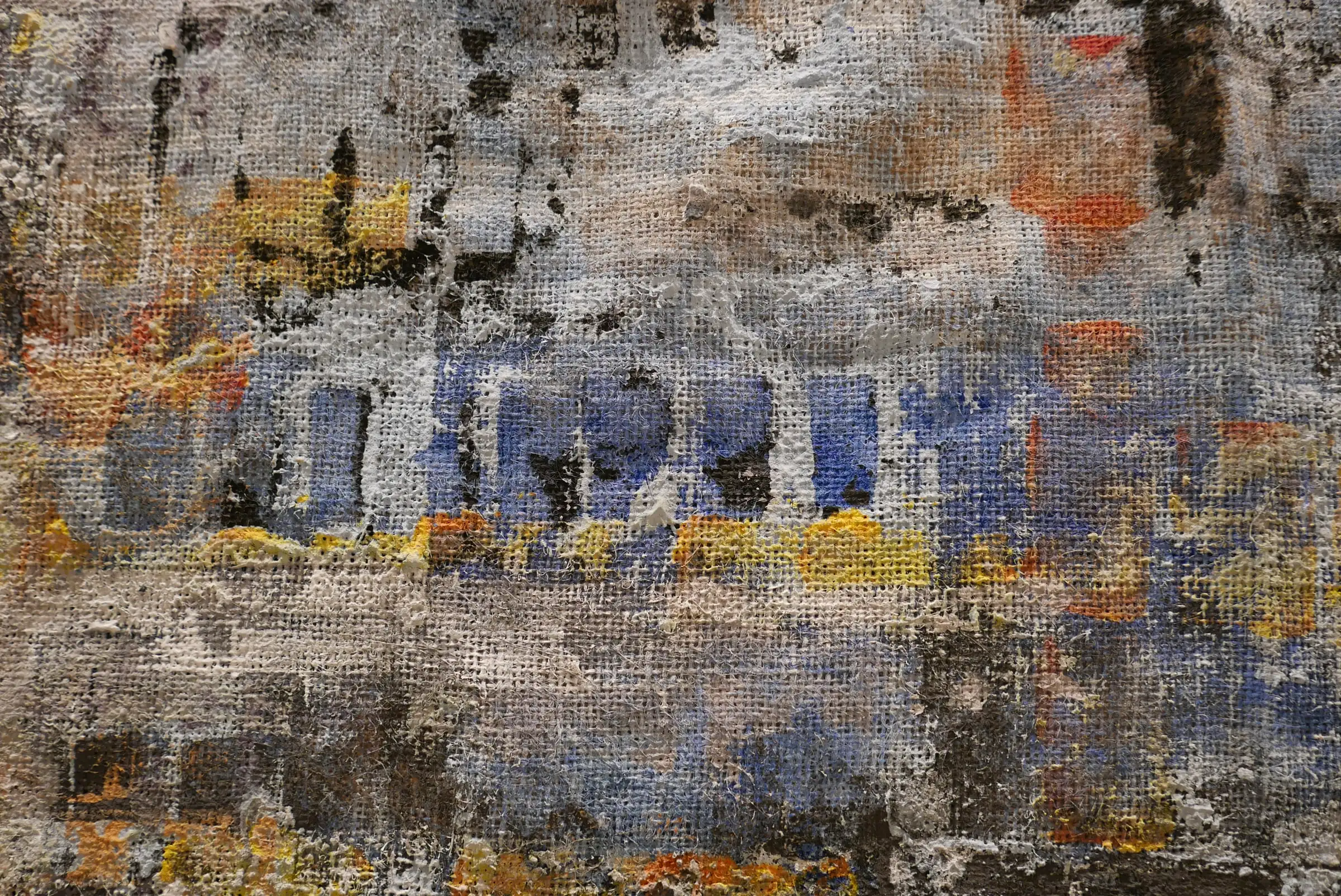 Detalle de Paisaje entre nubes: grises, azules y ocres en relieve sobre la trama de la arpillera