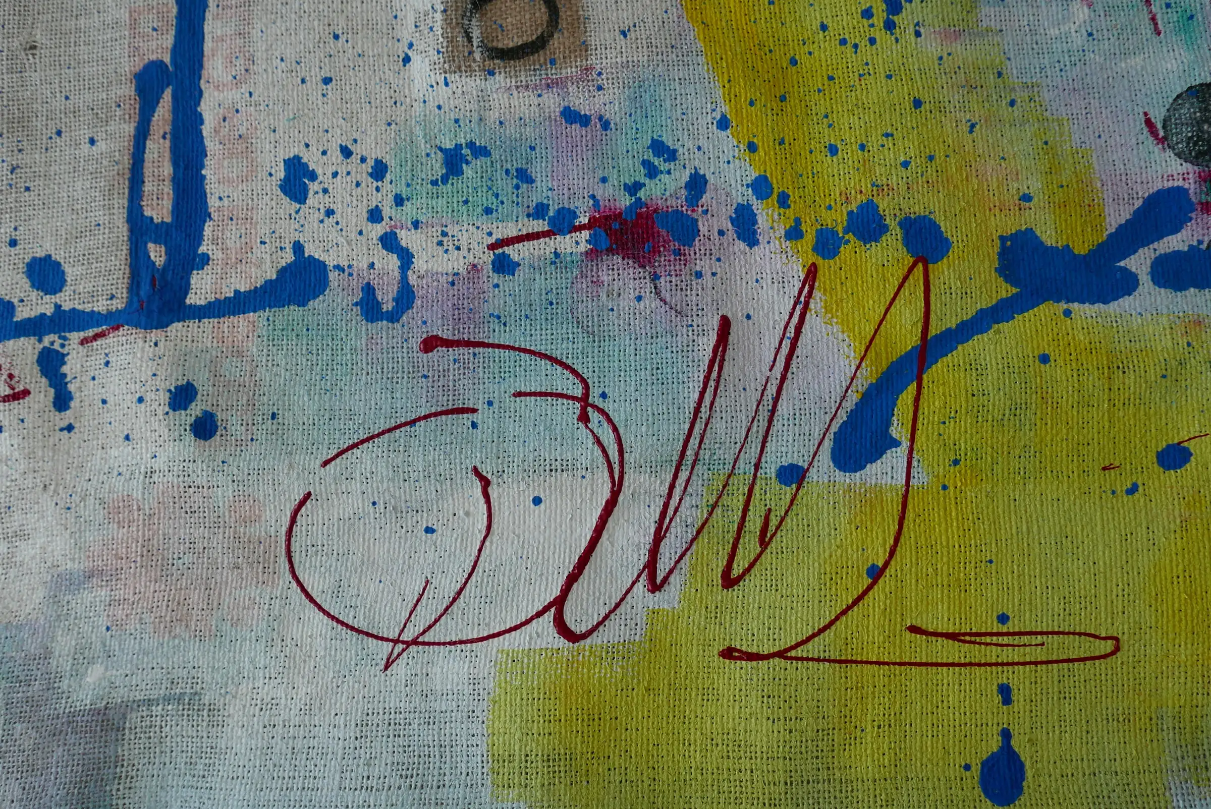 Detalle de Umbral: firma en granate y salpicaduras azules sobre amarillo
